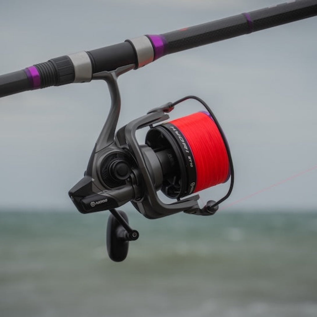 Fishing rod with a red spool against a blurred water background