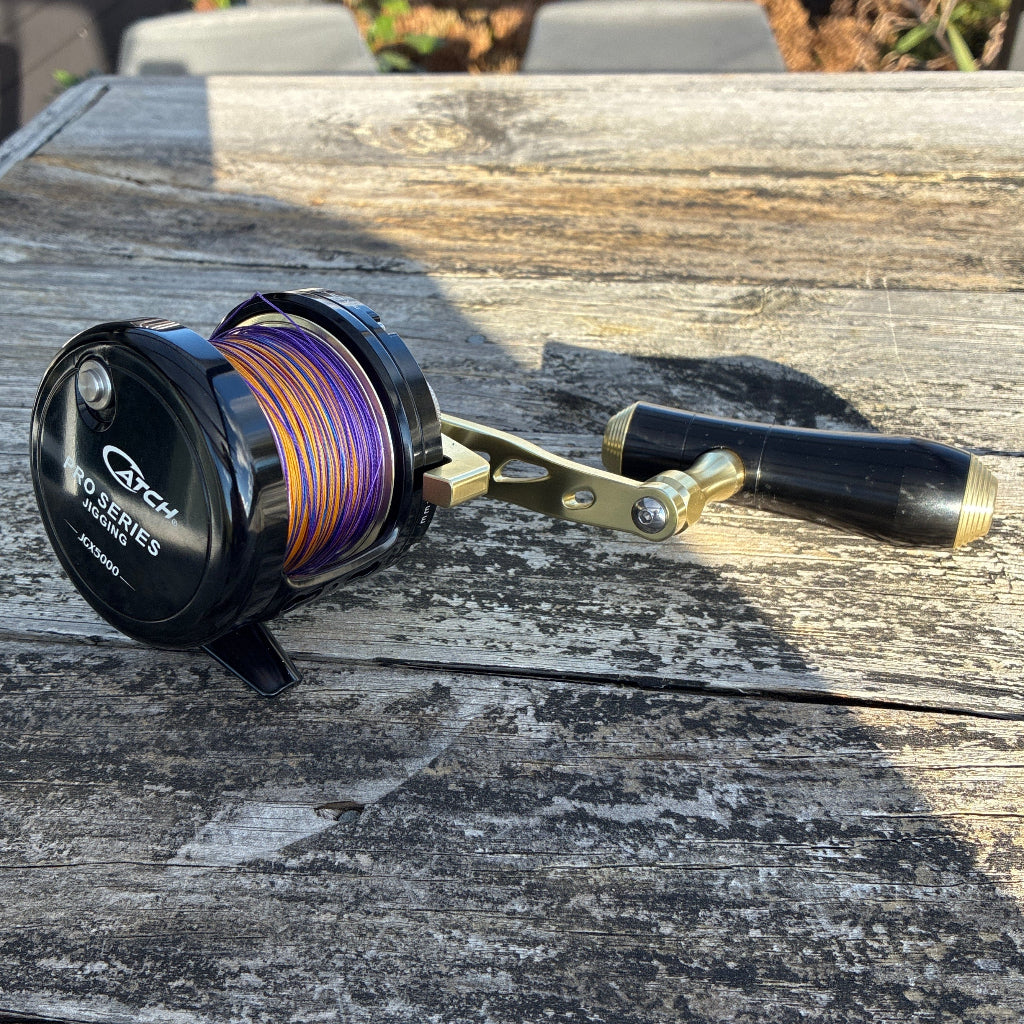 Fishing reel on a wooden surface with blurred outdoor background