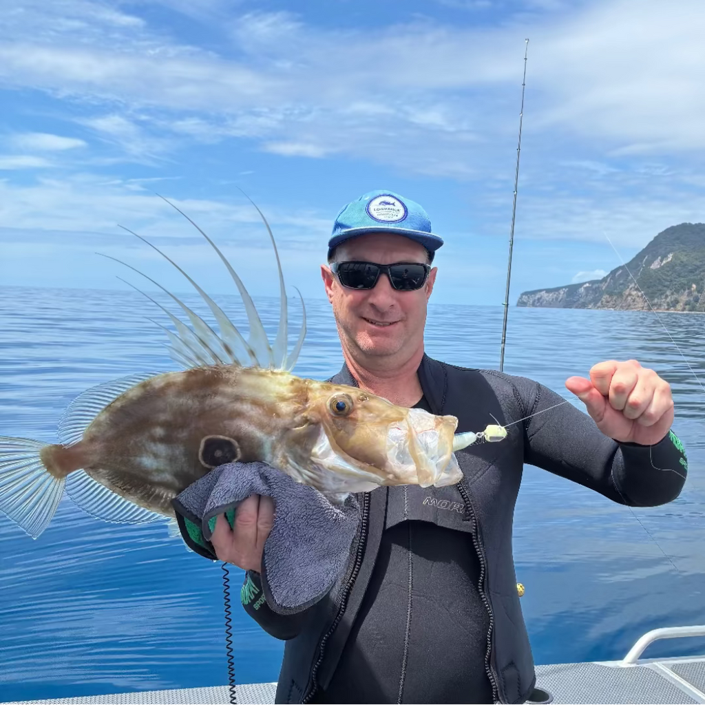 Man holding a large fish caught on a fishing trip with a scenic background