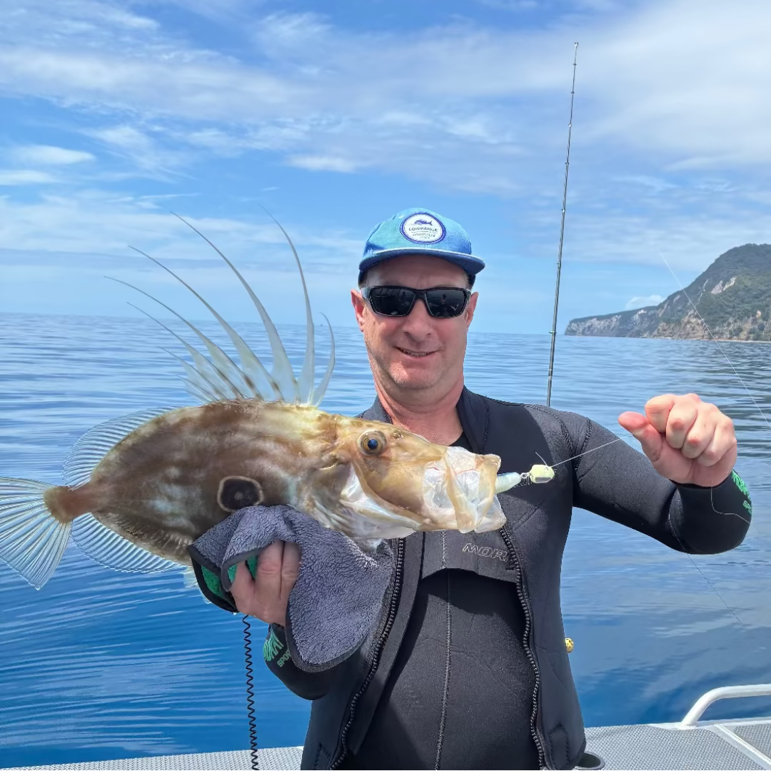 Man holding a large fish caught on a fishing trip with a scenic background