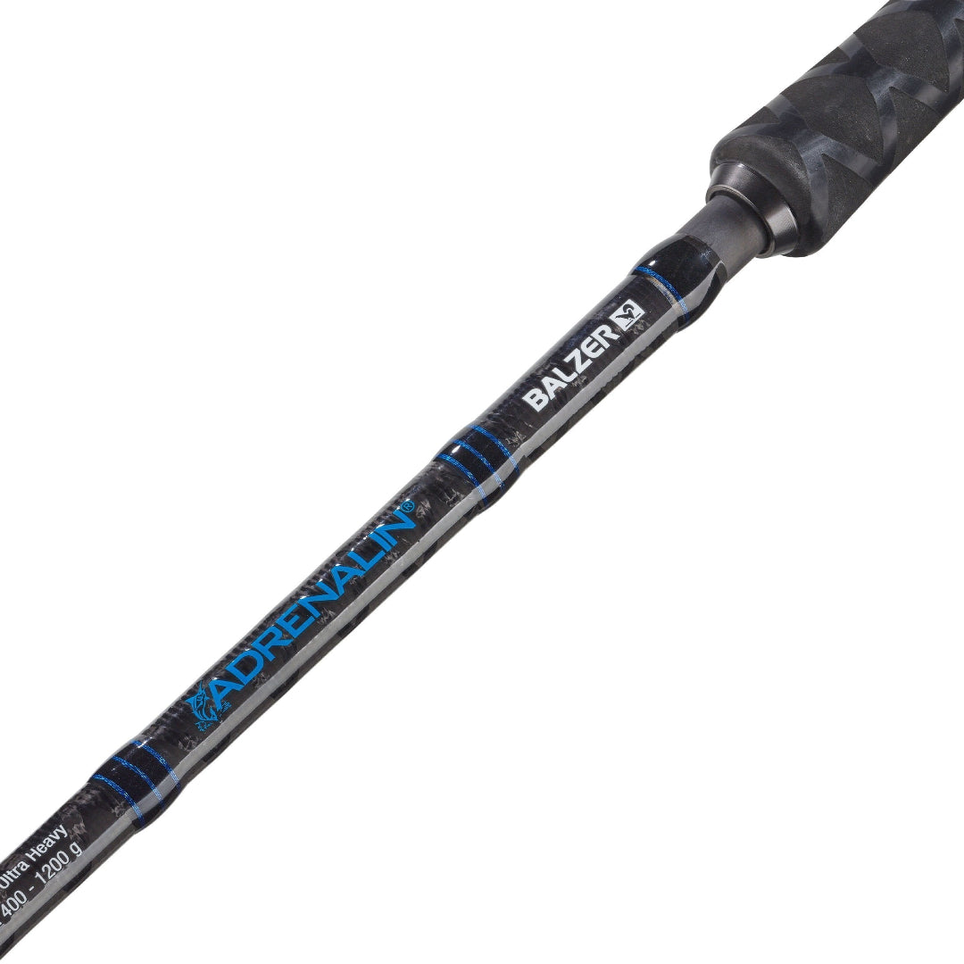 A close-up diagonal shot of a Balzersfjærd Adrenalyn fishing rod blank, showing the black and blue carbon fiber pattern, white branding, and a textured black handle grip against a solid white background.