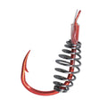 A fishing hook with a metallic red body, a black metal spring, and a clear plastic tip with red thread wrapping, shown against a plain white background.