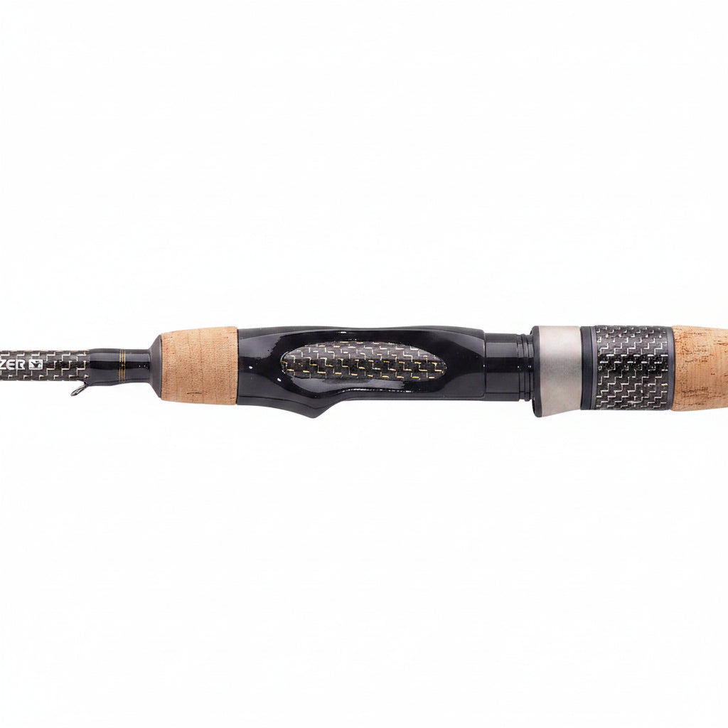 A close-up of a fishing rod showing the black and gray carbon fiber shaft, the cork and black handle, and the cork-wrapped grip section.