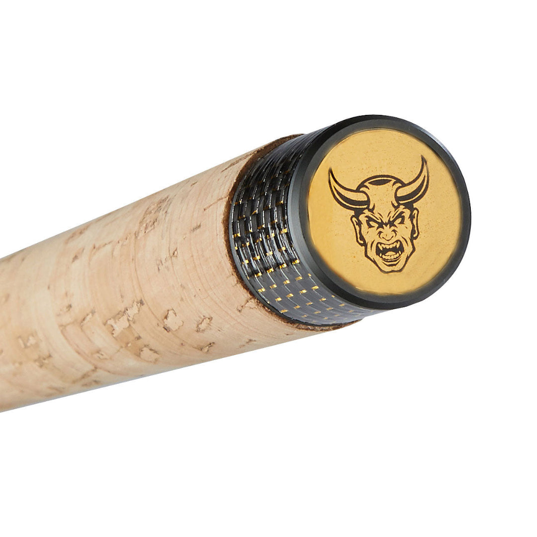 Close-up of a golf club shaft tip with a natural cork finish, a black textured band, and a gold end cap featuring a black horned demon logo.