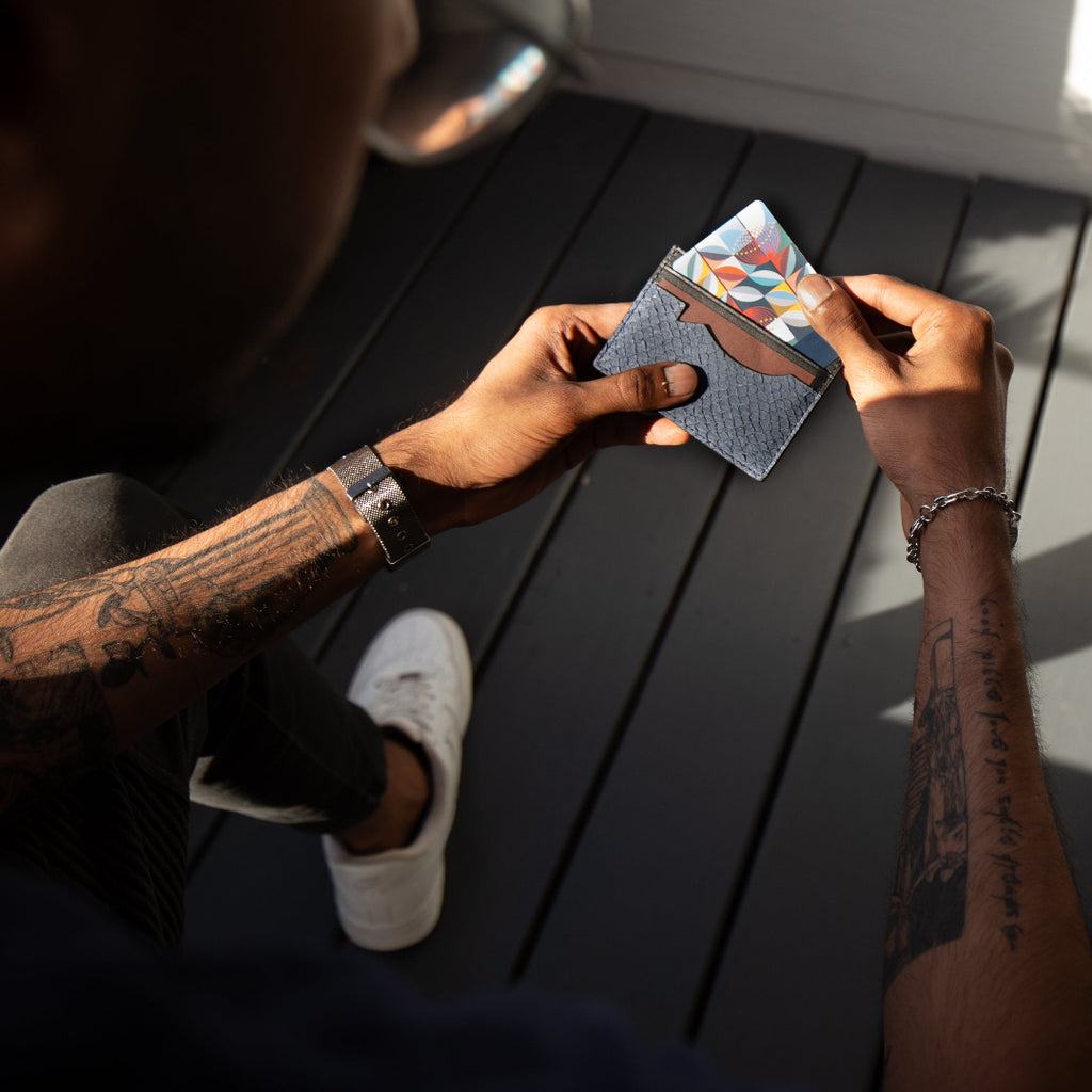 Person holding a small wallet with a colorful design on a wooden surface