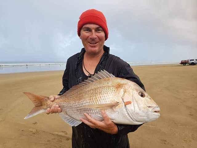 Surfcasting reel in use on New Zealand beach demonstrating long distance casting performance